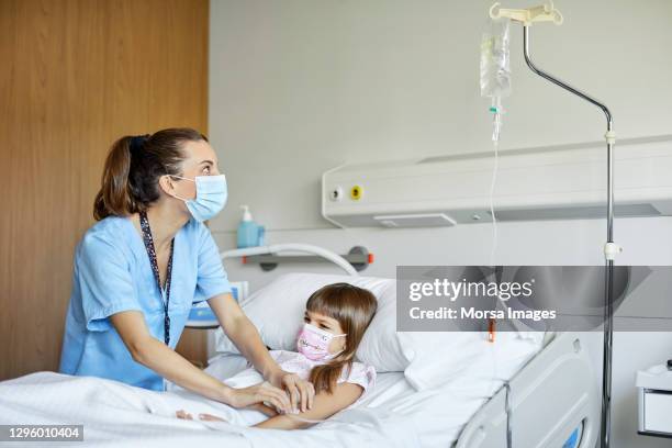 nurse by patient checking iv drip in hospital - girl in hospital bed sick stock pictures, royalty-free photos & images