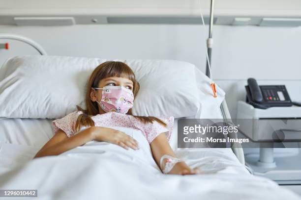 sick girl lying on bed in icu during covid-19 - krankheit stock-fotos und bilder