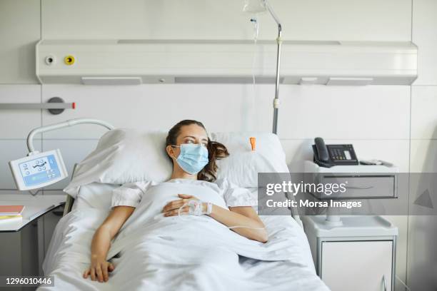 sick female lying on bed in icu during covid-19 - face mask coronavirus photos et images de collection