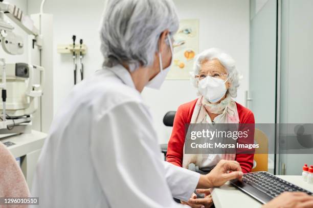 doctor discussing with aged woman in hospital - eye doctor and patient stock pictures, royalty-free photos & images