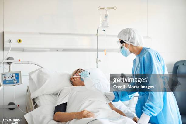 doctor consoling patient in icu during covid-19 - intensive care unit stock pictures, royalty-free photos & images