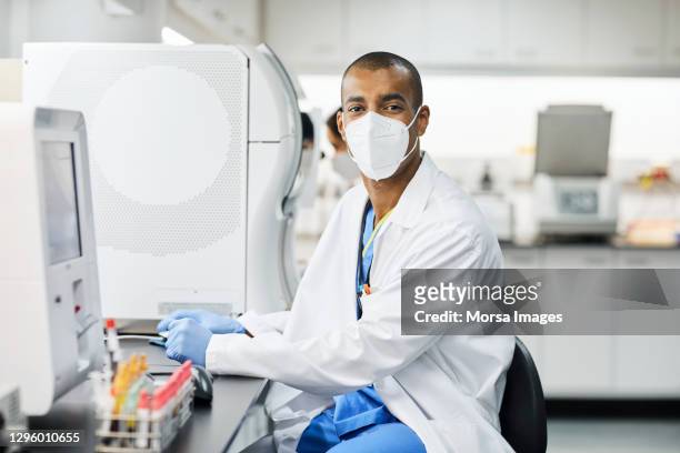 male doctor working in laboratory during covid-19 - microbiologie stockfoto's en -beelden