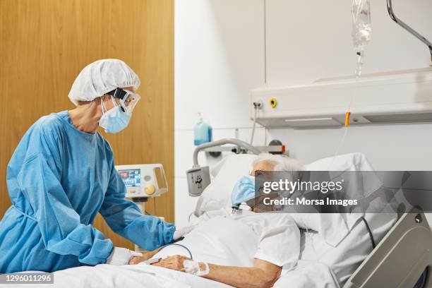 doctor consoling patient in icu during covid-19 - person on ventilator stock pictures, royalty-free photos & images