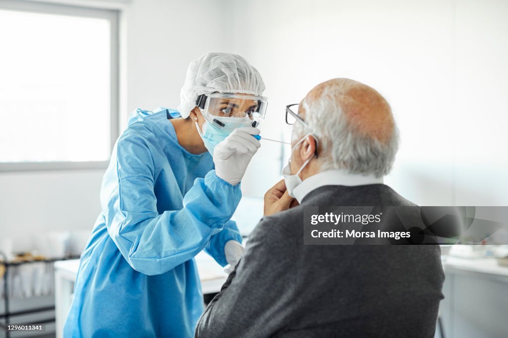 Doctor taking swab test sample of elderly patient, PCR.