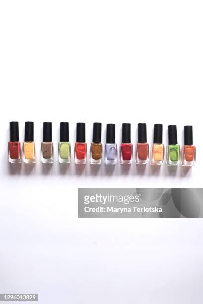 row of multi-colored nail polishes on a white background. - black painted toes stock-fotos und bilder