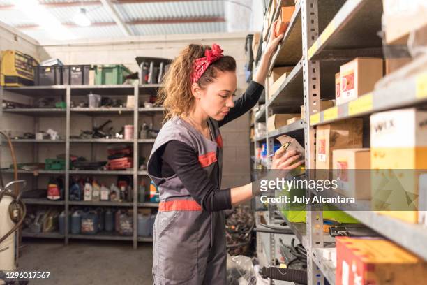 de vrouw in een reserveonderdelenopslag in een autoworkshop onderzoekt de dozen en selecteert de verschillende delen - part of stockfoto's en -beelden