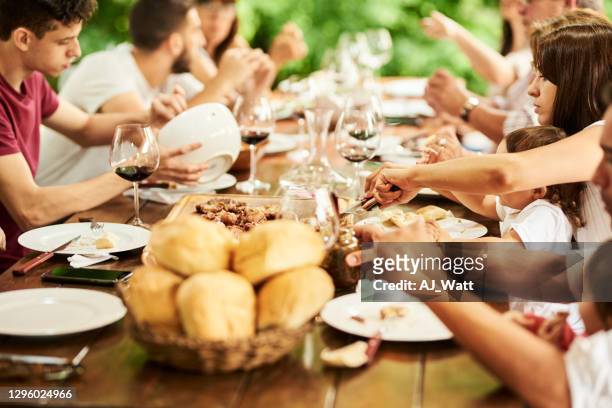 multi-generational family having dinner outside around a table - large group of people eating stock pictures, royalty-free photos & images