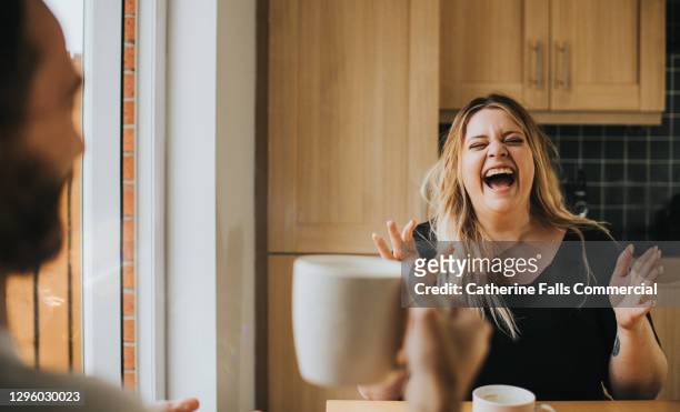 man and woman drink coffee / tea together as woman laughs hysterically - lachen stock-fotos und bilder