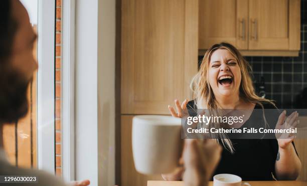 man and woman drink coffee / tea together as woman laughs hysterically - rire aux éclats photos et images de collection