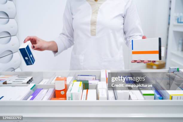 young pharmacist looking for medicines in the drawer - apotheek stockfoto's en -beelden