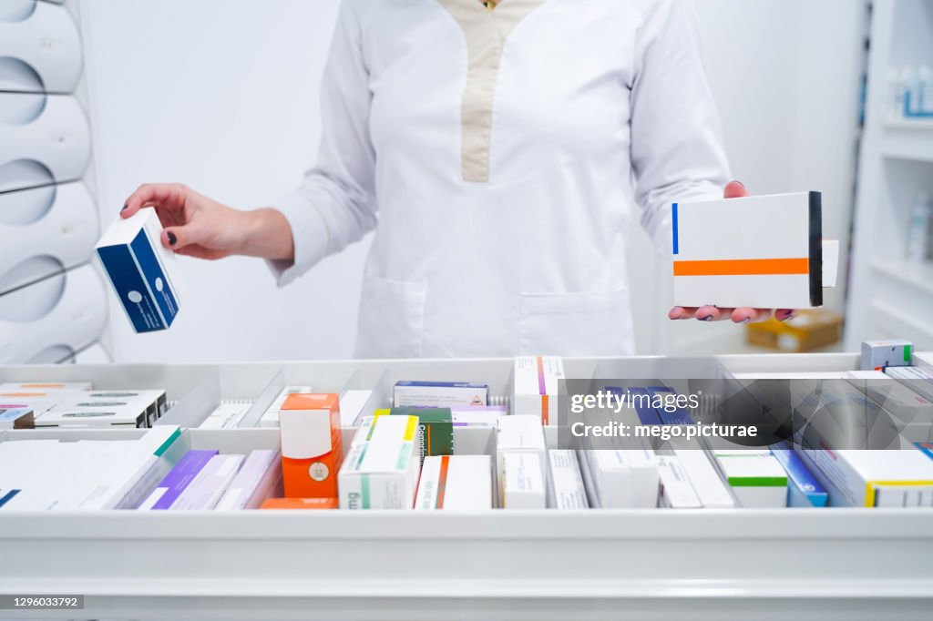 Young pharmacist looking for medicines in the drawer
