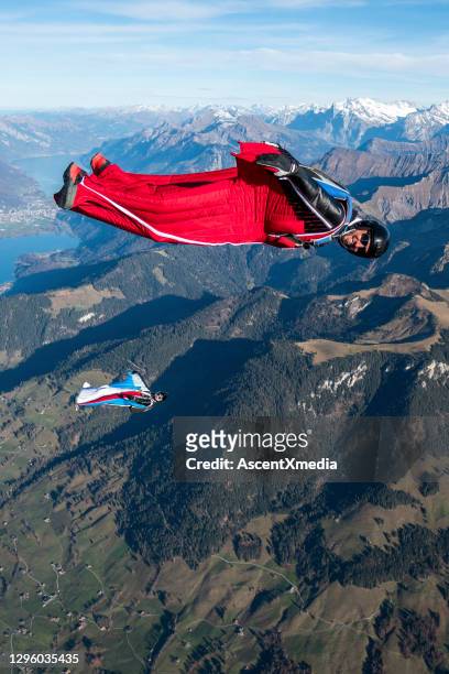 wing suit fliers glide through clear skies - wing suit stock pictures, royalty-free photos & images