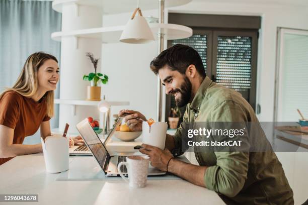 una giovane coppia lavora da casa e mangia pasta in cucina - pausa pranzo foto e immagini stock