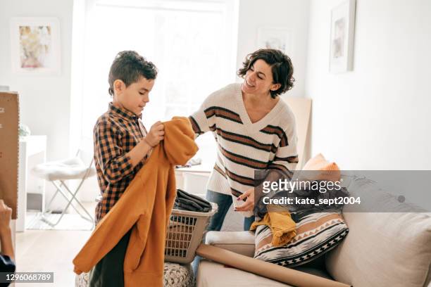 lavando roupa com crianças. mãe ensinando filho como dobrar as roupas - afazeres domésticos - fotografias e filmes do acervo