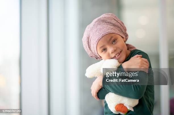 jovem com câncer abraçando seu ursinho de pelúcia - célula cancerígena - fotografias e filmes do acervo