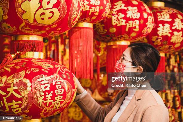 asian woman wearing a chinese new year theme face mask shopping for chinese new year decorations - chinese new year home stock-fotos und bilder