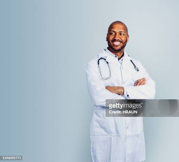 lächelnder männlicher arzt steht mit gekreuzten armen - doctors in africa stock-fotos und bilder