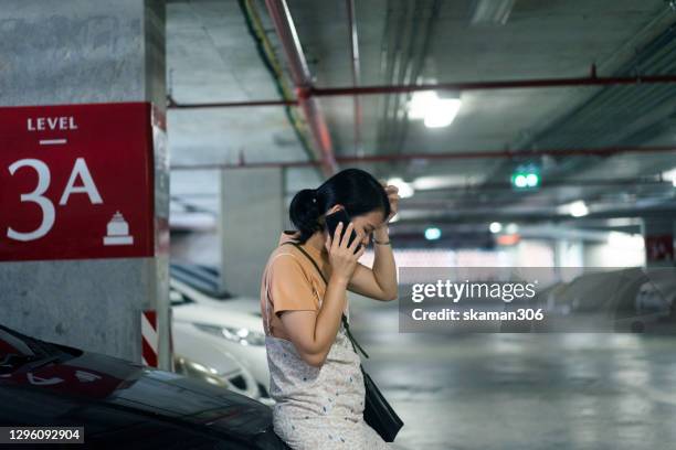 asian female very serious and call mechanic and car insurance  about car breakdown at indoor parking lot - overheated stock pictures, royalty-free photos & images