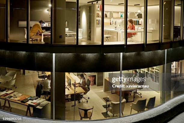 profesionales del diseño trabajando tarde en la oficina de dos pisos - bloque de oficinas fotografías e imágenes de stock