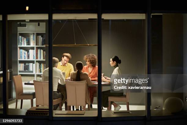 corporate team working late in modern office - photographed through window stock pictures, royalty-free photos & images