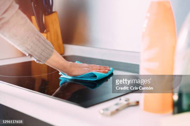 female hand cleaning induction stove with blue rag - hob fotografías e imágenes de stock