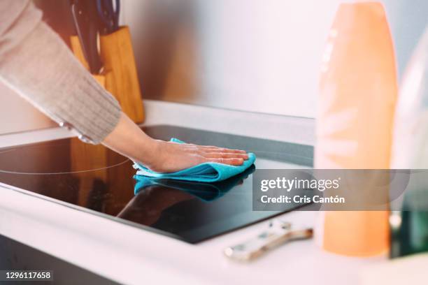 female hand cleaning induction stove with blue rag - cleaning kitchen stock pictures, royalty-free photos & images