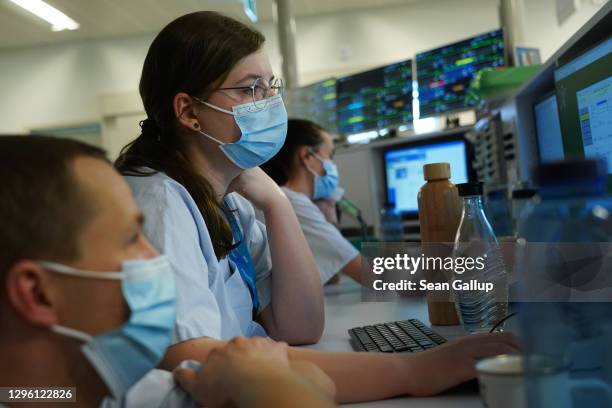 Hospital staff sit at computer monitors as monitors placed above show data from individual patients in the Covid intensive care unit at Leipzig...