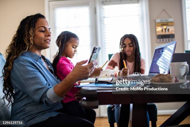 mother working from home while daughters homeschool - call us stock-fotos und bilder