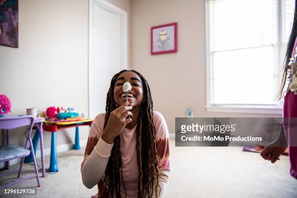 teenage girl being silly with a spoon on her nose - funny black girl stock-fotos und bilder
