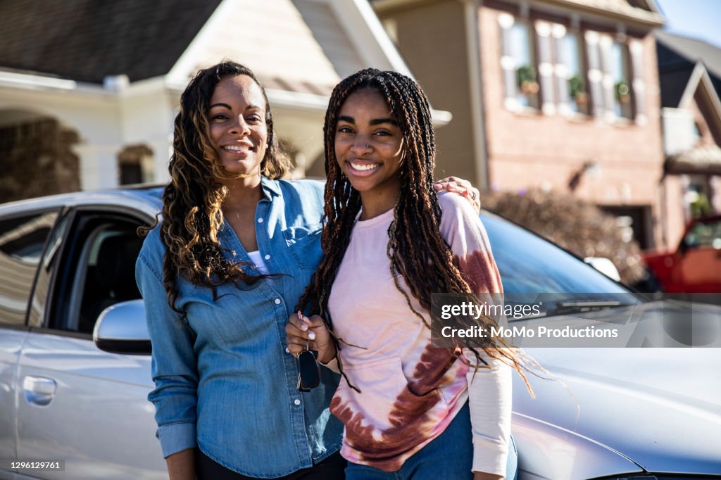 Portrait of mother and teenage girl with her first car