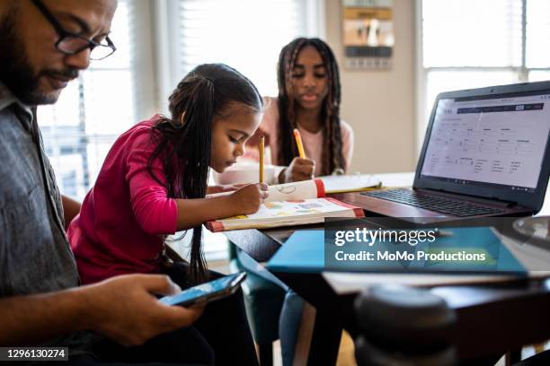 father working from home while daughters homeschool - indian family in their 40's with kids imagens e fotografias de stock