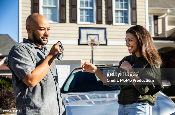 father handing car keys to teenage daughter - daughter car stock pictures, royalty-free photos & images