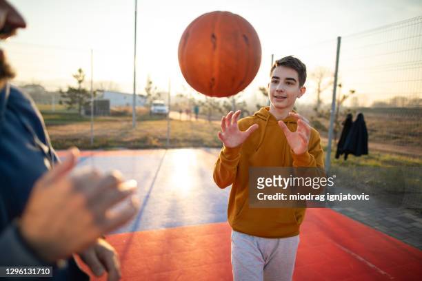 teenager genießt zusammen zeit mit seinem vater auf dem basketballplatz - pass stock-fotos und bilder