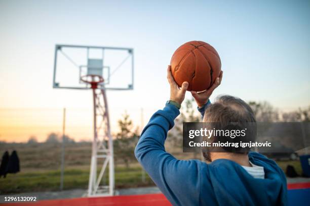 mature man playing basketball on sports court - mature men playing basketball stock pictures, royalty-free photos & images