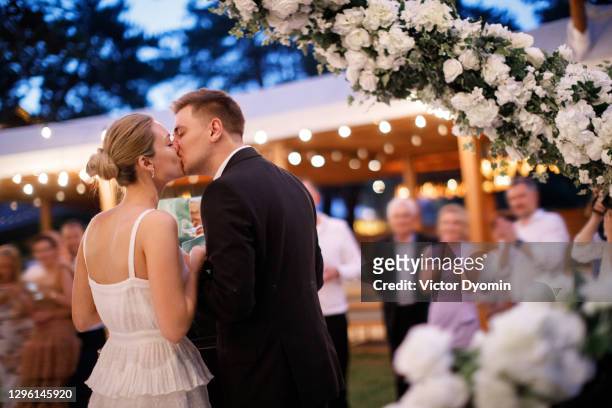 beautiful couple is kissing at the celebration - ceremony stock pictures, royalty-free photos & images