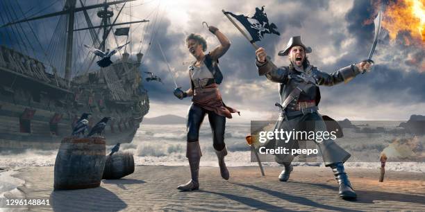 pirates on beach holding flag and cutlass near pirate ship - pirata imagens e fotografias de stock