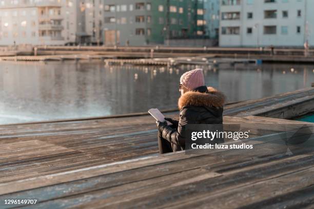 senior woman reading a book outing the winter sun - paperback stock pictures, royalty-free photos & images