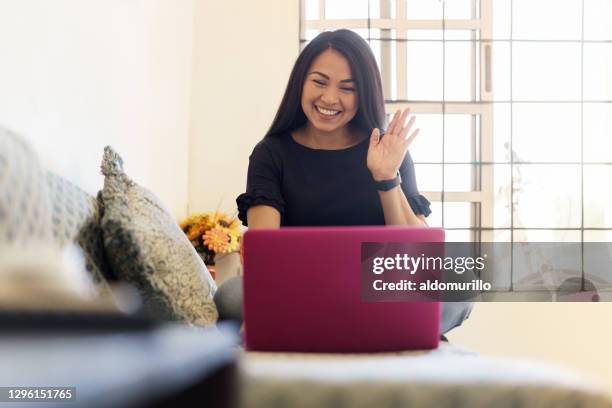 mujer sonriente feliz sentada en el sofá y usando el ordenador portátil - masters degree fotografías e imágenes de stock