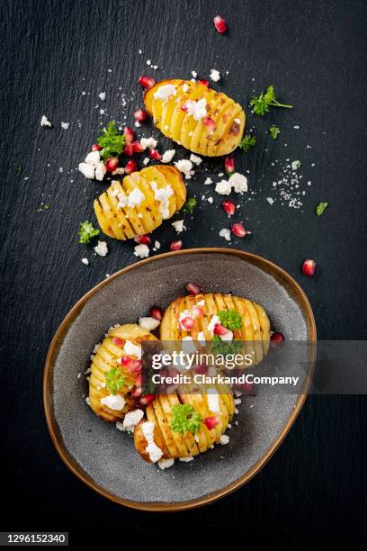 hasselback potatoes with feta cheese and pomegranate seeds. - baked potato stock pictures, royalty-free photos & images