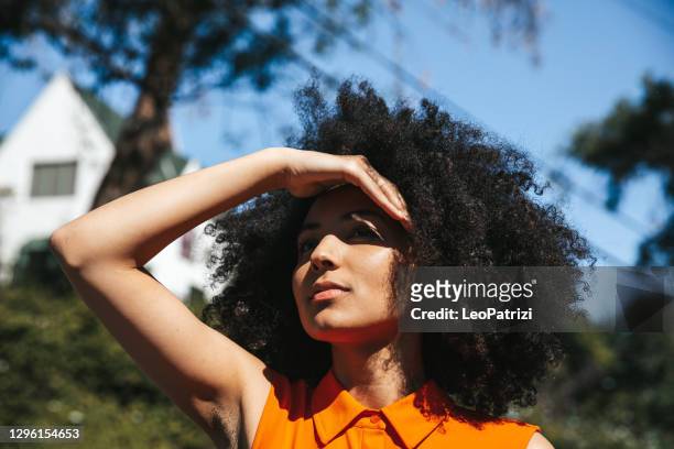 vrouw met afro haar dat haar ogen van de zon behandelt - sun stockfoto's en -beelden