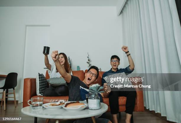 asiatische chinesische enge freunde sehen ein sportspiel im fernsehen zusammen zu hause - family game night stock-fotos und bilder