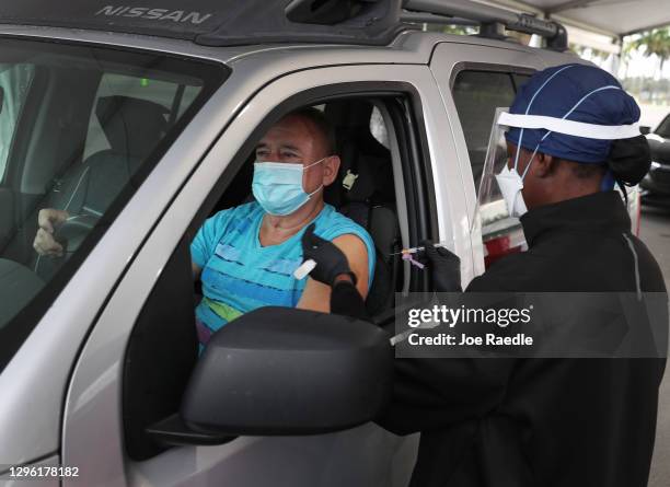 Armando Bravo receives a COVID-19 vaccine from a healthcare worker at a drive-thru site at Tropical Park on January 13, 2021 in Miami, Florida....