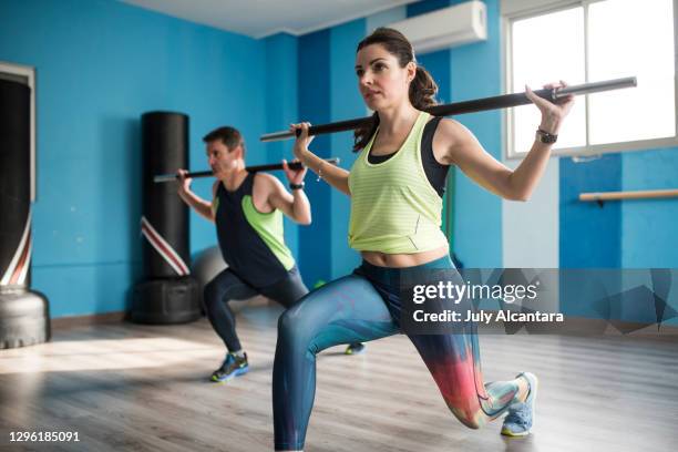 attractive 40 year old woman performs abdominal and barbell workout with a man in a gym room - joint effort stock pictures, royalty-free photos & images