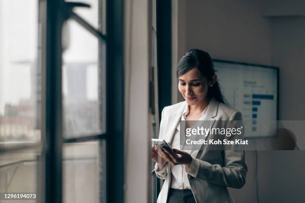 belle femme d’affaires indienne utilisant son téléphone portable dans le bureau - entrepreneur stock photos et images de collection