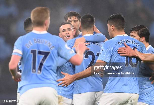 Phil Foden of Manchester City is congratulated by teammates John Stones and Joao Cancelo after scoring their team's first goal during the Premier...