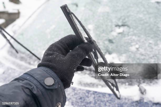 a person holds an icy car wiper while cleaning it on a snowy day in winter. germany. - auto wipers stock pictures, royalty-free photos & images