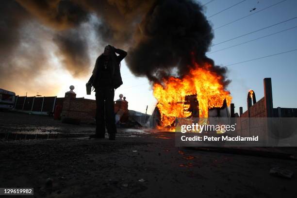 An activist looks on in front of a burning caravan, which was set ablaze by activists to be used as a barricade, as evictions begin at Dale Farm...