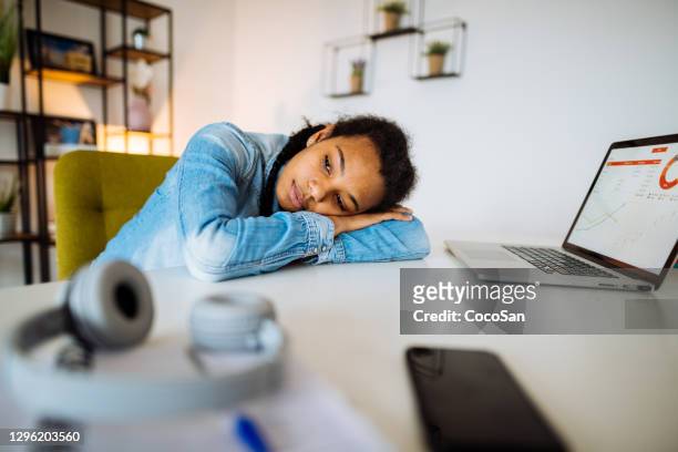 African-American Gen-Z woman working at home during lockdown. Woman resting on the desk and daydreaming