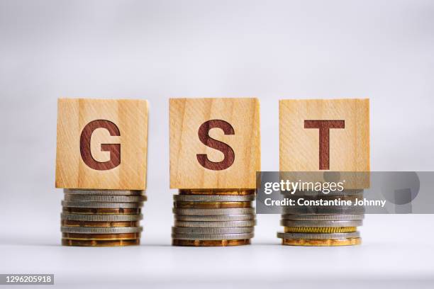 gst word on wood block on top of coin stack. value added tax. - vat imagens e fotografias de stock