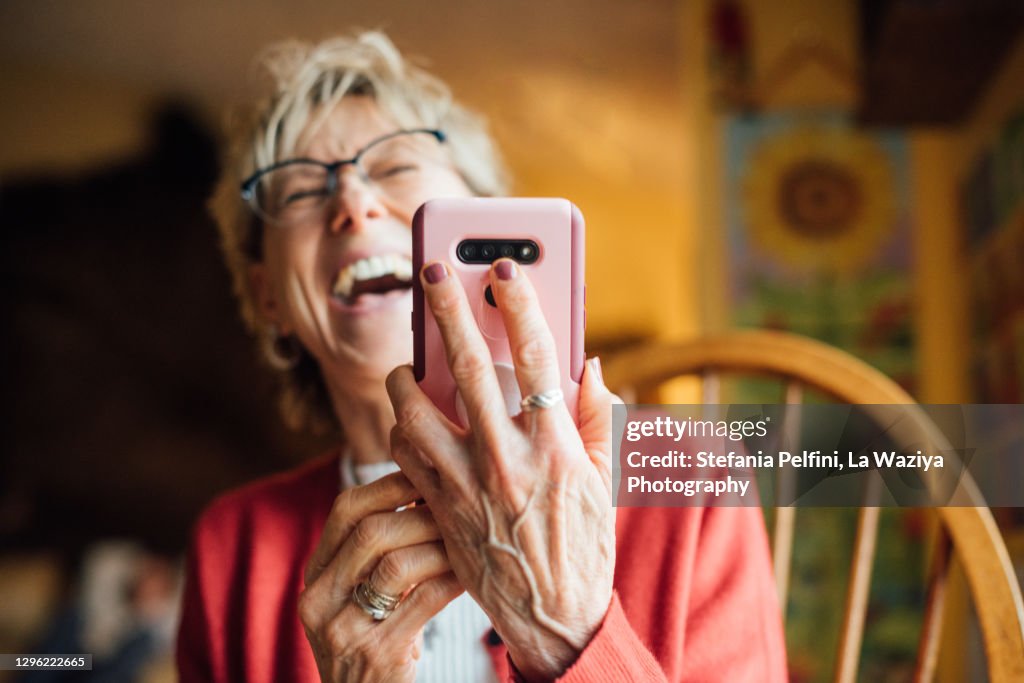 Senior woman laughing while using her smartphone